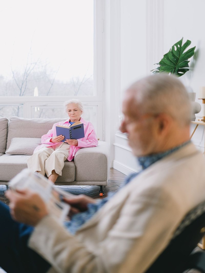 Una abuela leyendo un libro en el sofá, acompañada, en una sala acogedora y bien iluminada