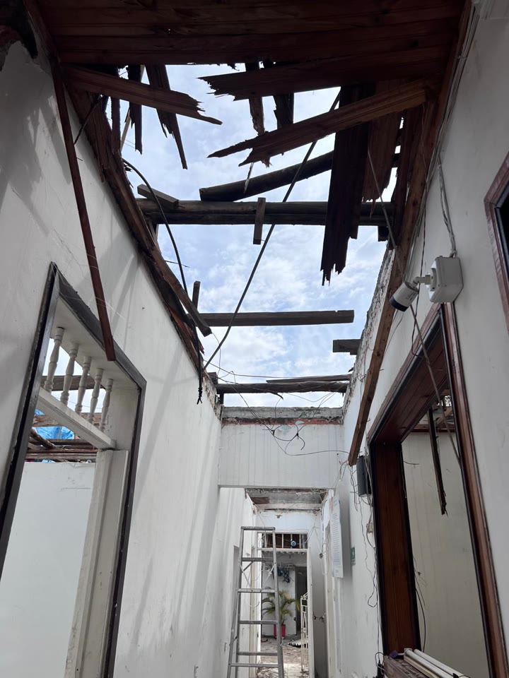 El techo del corredor de nuestro hogar destruido por el terremoto, con las vigas de madera y el cielo visibles